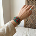 Hand wearing a colorful bracelet with a neutral background