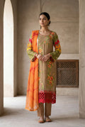 Woman in traditional outfit with floral patterns standing in a sunlit room.