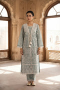Woman in a light blue traditional outfit standing in a sunlit room with architectural elements.