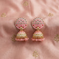 Pair of pink and gold earrings on a pink fabric background