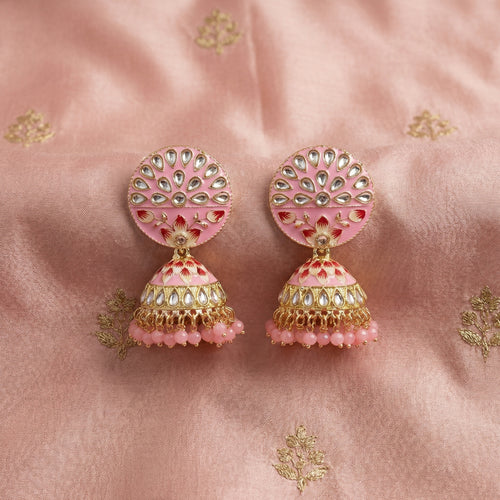 Pair of pink and gold earrings on a pink fabric background