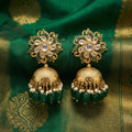 Gold and green earrings on a green fabric background
