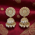 Ornate gold and pearl earrings on a red fabric background