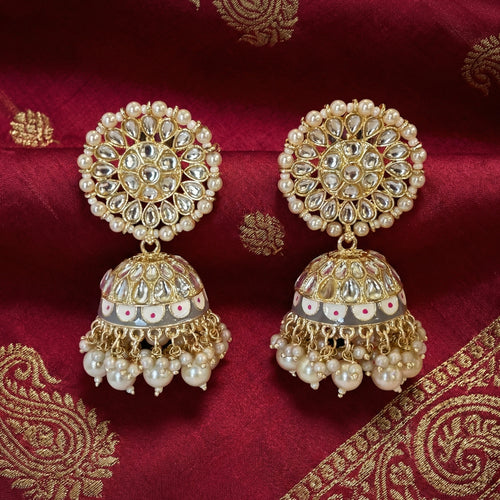 Ornate gold and pearl earrings on a red fabric background