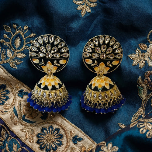 Ornate earrings on a blue embroidered fabric background