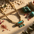 Necklace with turquoise stones on a textured surface with decorative elements