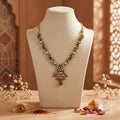 Amber gemmed necklace on a mannequin bust with decorative elements on the counter with a warm-toned background.
