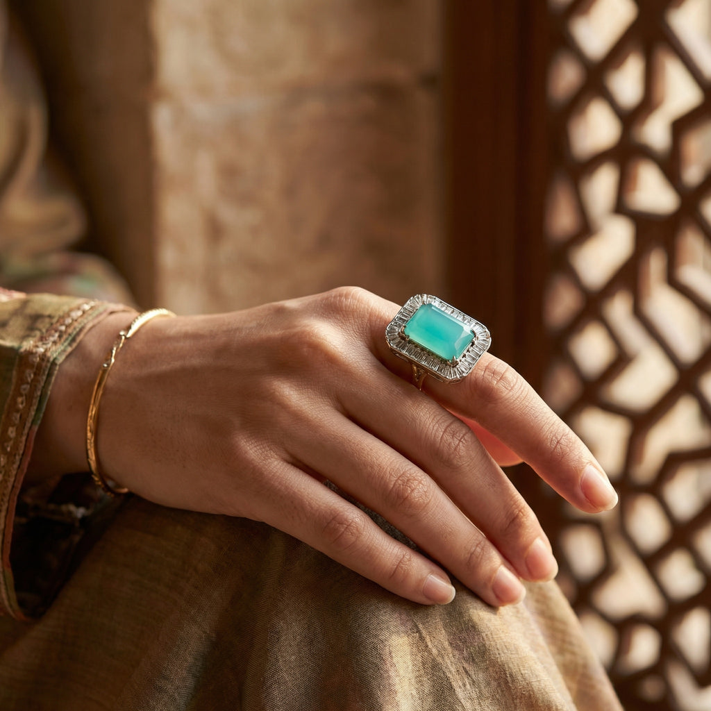 Hand wearing a turquoise ring with diamond accents against a warm-toned background