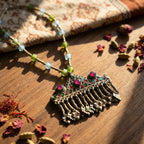 Decorative necklace with gemstones on a wooden surface with dried flowers