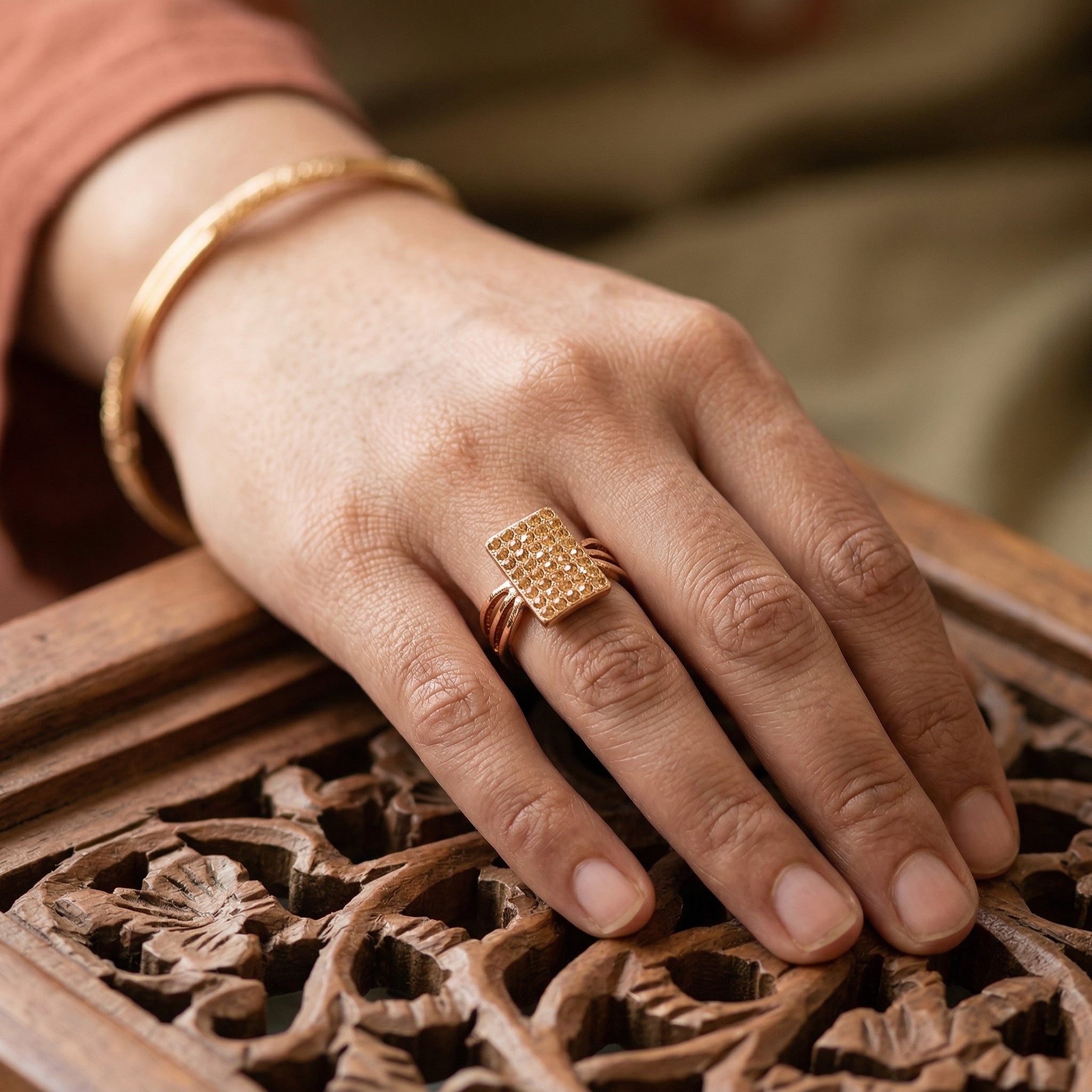 Hand wearing a gold ring on a wooden surface