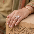 Hand wearing a decorative ring on a textured surface