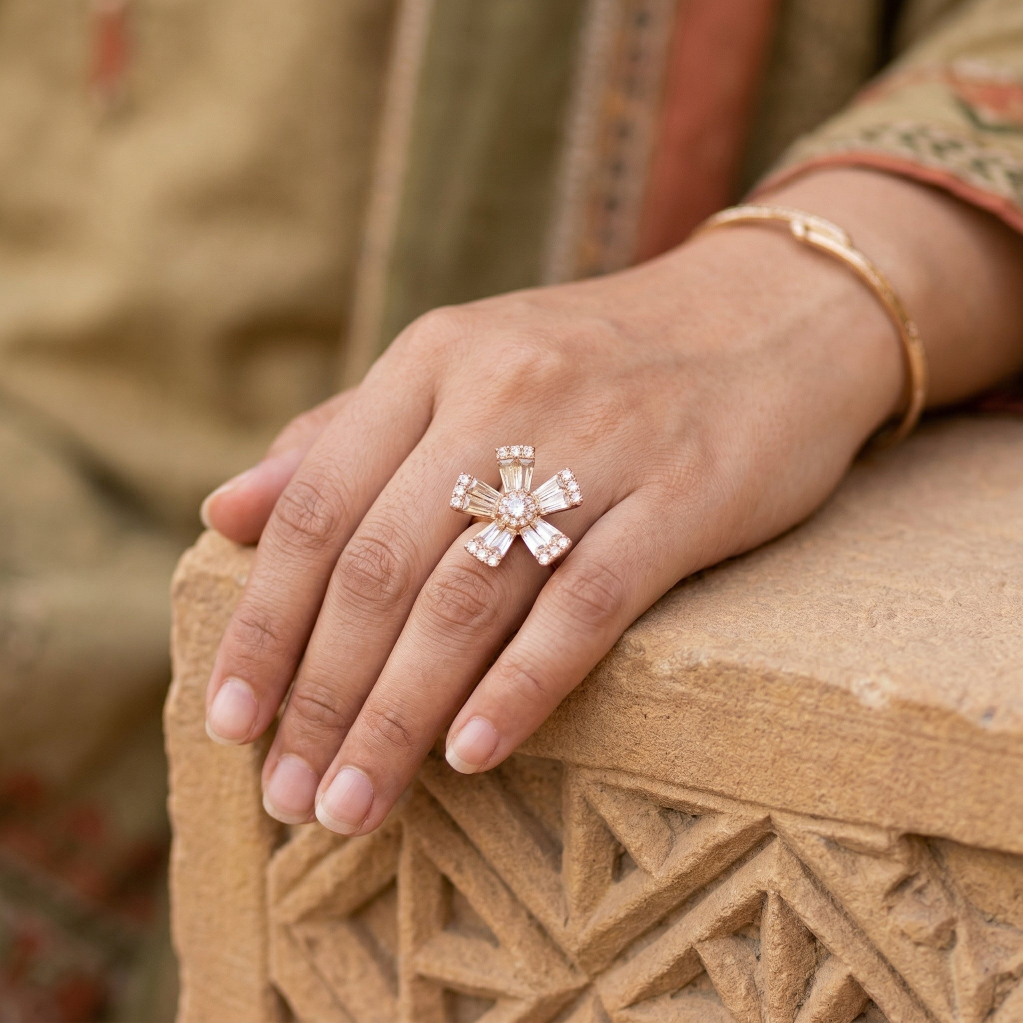 Hand wearing a decorative ring on a textured surface