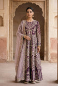 Woman in a traditional embroidered outfit standing in front of an architectural background