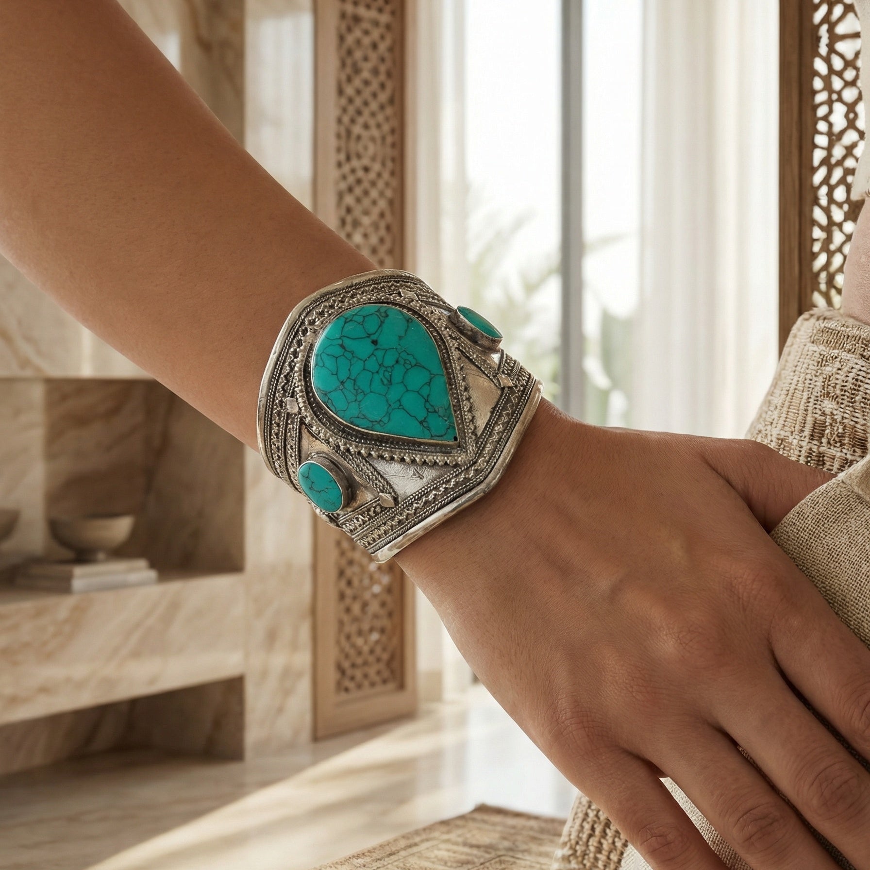Turquoise stone cuff on a wrist with a blurred indoor background